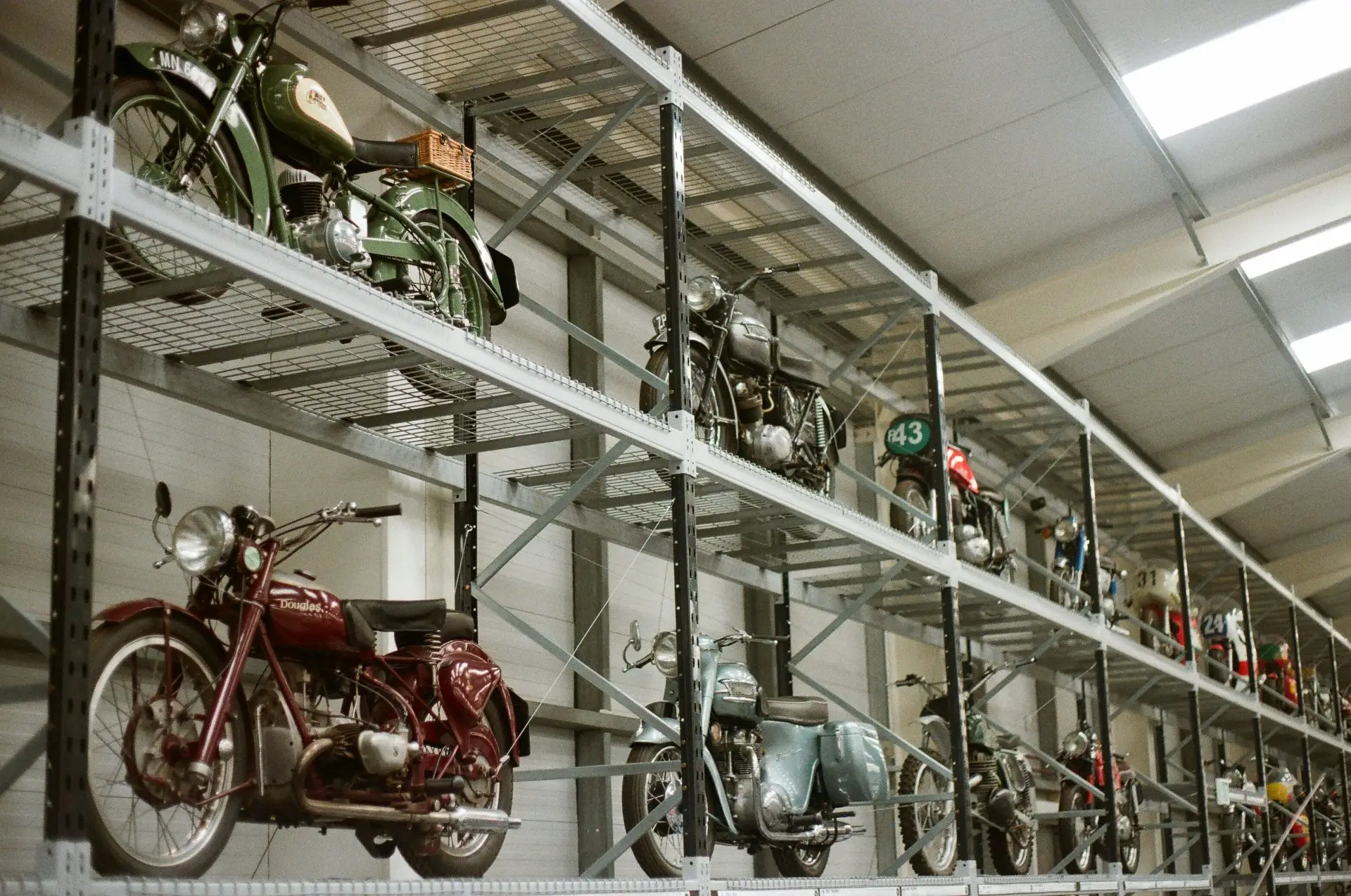 Vintage motorcycles displayed on shelves in a museum.